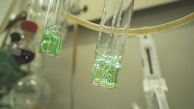 Close-up of two test tubes boiling over a fire. against the background of the laboratory and other test tubes and tubes. Slow motion.120 frames per second.
