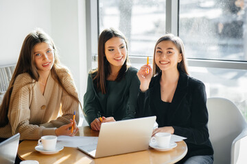 A group of young girls sit in an office and work at computers. Communication and training online.