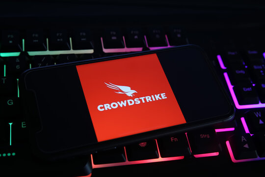 Viersen, Germany - May 1. 2021: Closeup of mobile phone screen with logo lettering of crowdstrike cyber security company on computer keyboard (focus on upper part of bird logo)