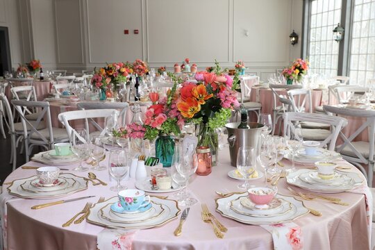Table set up for bridal shower on bright spring day with flowers in the middle and vintage tea cups on each plate