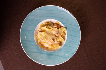 pasta with salmon and cheese on a blue plate top view.