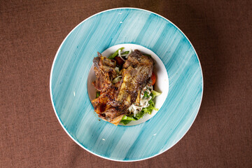 braised lamb rib with fresh salad on a plate top view.