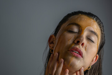 black haired woman with honey on her face