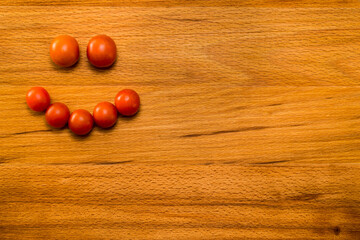 Happy smiley made with tomatoes on a wooden table