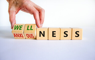 Wellness or anxiousness. Doctor turns cubes and changes the word 'anxiousness' to 'wellness'. Beautiful white table, white background. Psychological, wellness or anxiousness concept. Copy space.