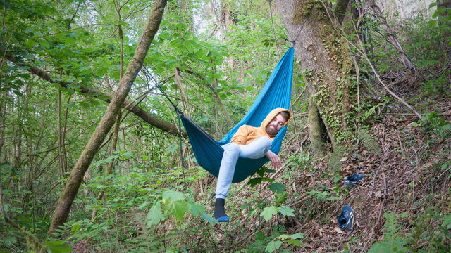 Hombre joven barbudo tumbado en hamaca en el bosque