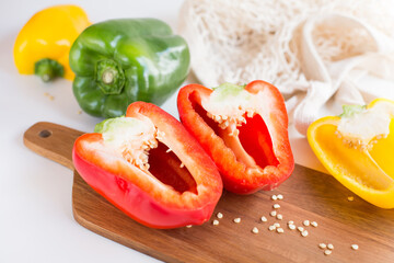 Ripe fresh peppers are on a wooden cutting board on the table in the kitchen.