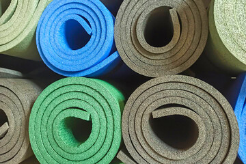 Colorful yoga mats. Fitness mats background, rolled into rolls, texture.