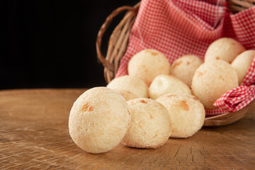Brazilian cheese bread, basket with checkered cloth with cheese breads on rustic wood, selective focus.