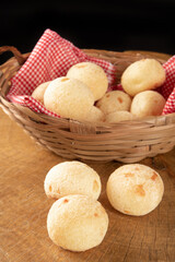 Brazilian cheese bread, basket with checkered cloth with cheese breads on rustic wood, selective focus.