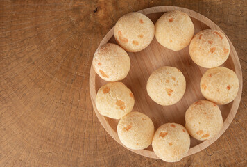 Brazilian Cheese bread, cheese breads arranged on wooden plate, on rustic wood, top view.