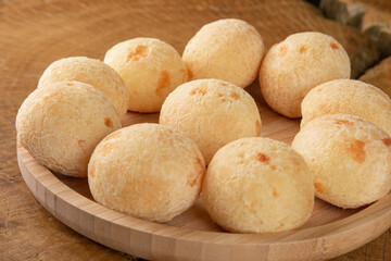 Brazilian Cheese bread, cheese breads arranged on wooden plate, on rustic wood, selective focus.