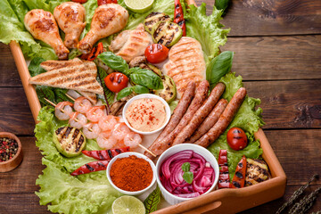 Composition of sausages, chicken, pork and shrimp prepared on grill, as well as vegetables prepared on grill with spices and herbs