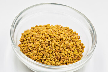 culinary ingredient fenugreek seeds on glass plate closeup