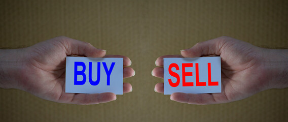 Hands holding card tickets with the words buy and sell. Concept for financial analysis, stocks market, economy