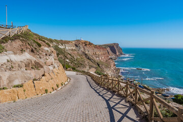  Sidewalk on cliffs with wooden fence and turquoise sea on the horizon at Assenta beach, Ericeira - Mafra PORTUGAL