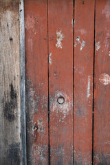 Details of an old, rusty, red, wooden door of a barn