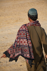 Desert dweller seen from behind with hat and scarf. The Thar is a desert and semi-desert region in...
