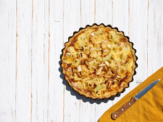 Homemade quiche of cauliflower and ham on white wooden background. Cooking at home. Top view. Copy space.