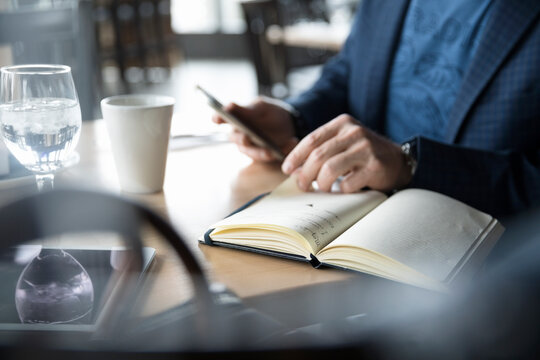 Businessman with journal and smart phone working at cafe table