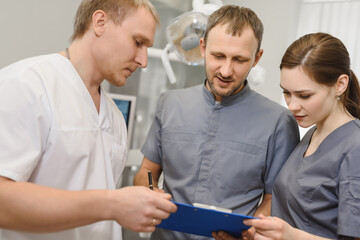 A group of experienced dentists discuss a dental treatment plan in the office of a modern dental clinic
