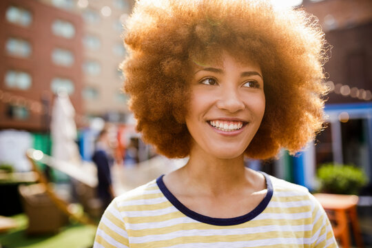 Portrait happy young woman with afro in sunny parking lot