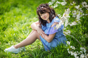 Fototapeta premium young beautiful brunette in a blooming garden in spring