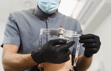 An experienced dentist placing a facial bow for woman patient to examine the bite. Modern technologies in dental treatment