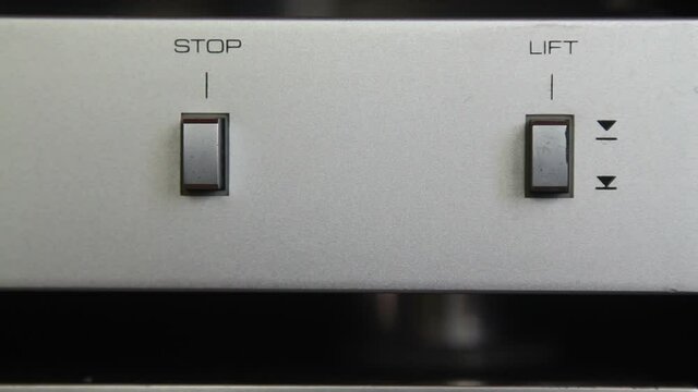 Close-up of a man finger pressing a stop button on the LP vinyl record player.