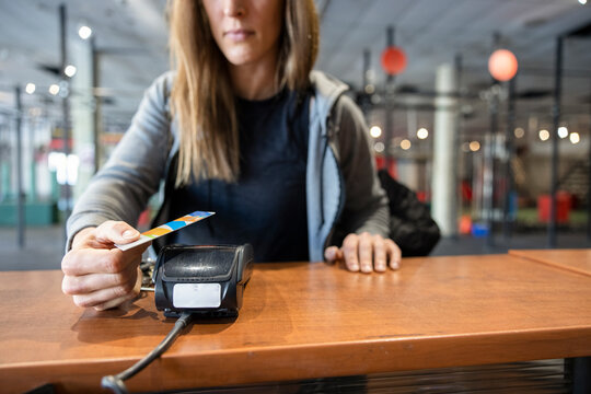 Close up woman paying for gym membership with smart card