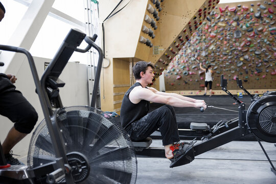 Young man using rowing machine in climbing gym