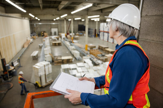 Supervisor looking down at man working in distribution warehouse
