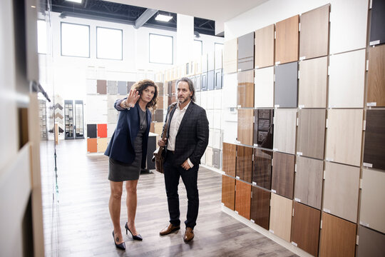 Saleswoman Showing Colors Of Cabinet To Customer In Kitchen Showroom