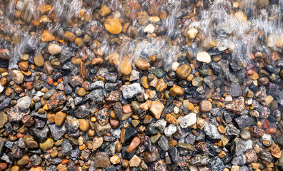 the water washes the multi-colored pebbles on the shore. flat lay.