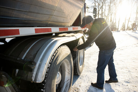 Driver checking tires of milk tanker truck