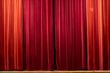 Closed washed out discolored vibrant red theatrical curtain with details and texture of the thick...