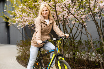 Lovely young woman posing with bike on the street of city, on sunny day