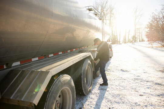 Driver checking tires of milk tanker truck