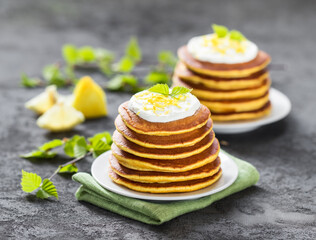 Pancakes with lemon and cream on a plate on a dark gray background