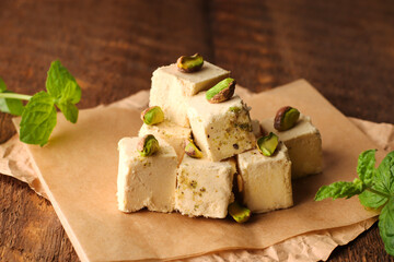 Halva with pistachios on parchment paper on a wooden background. Natural vegan product. Turkish, Arab and Jewish national sweets. Traditional oriental dessert Chekme.