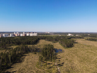 View from the height of the road in the field, the forest on the outskirts of the city with residential high-rise buildings. Panoramic beautiful photo from a drone. Picturesque photo wallpaper, screen