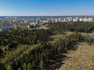 View from the height to the outskirts of the city with residential high-rise buildings and forests. Panoramic beautiful photo from a drone. Picturesque photo wallpaper, screensaver, cover, background.