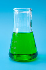 Chemical research, lab test and scientific experiment concept with green coloured liquid  solution in glass erlenmeyer conical flask isolated on blue laboratory background