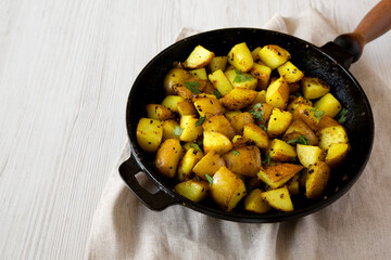Homemade Roasted Potatoes with Mustard Seeds in a cast-iron pan, side view. Space for text.