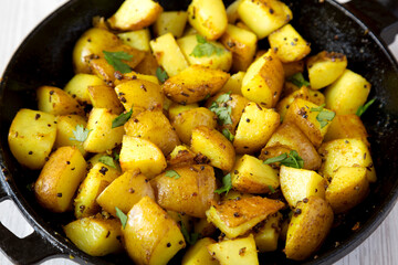 Homemade Roasted Potatoes with Mustard Seeds in a cast-iron pan, side view. Close-up.