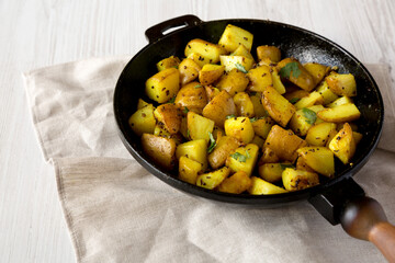 Homemade Roasted Potatoes with Mustard Seeds in a cast-iron pan, side view.