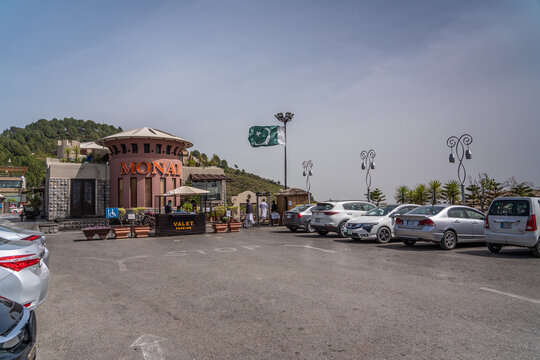 Islamabad, Pakistan, March 2021, entrance and parking area for "The Monal Restaurant at Margalla Hills in Islamabad mountain range with the Pakistan flag dancing in the wind 