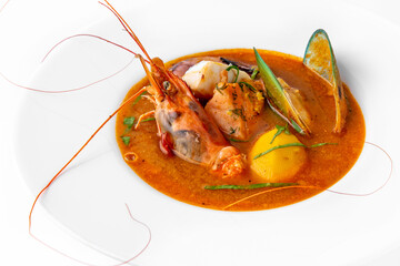 Delicate spicy cream seafood soup with shrimp, mussels, octopus and salmon. Banquet festive dishes. Gourmet restaurant menu. White background.