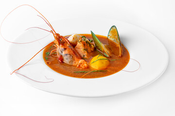 Delicate spicy cream seafood soup with shrimp, mussels, octopus and salmon. Banquet festive dishes. Gourmet restaurant menu. White background.