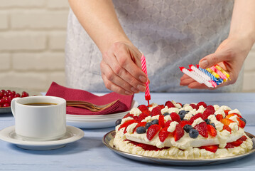 Obraz na płótnie Canvas female hand sets birthday candles on homemade strawberry cake. strawberry pie and birthday candles